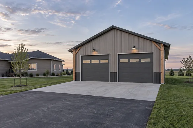 Detached post-frame garage with two overhead doors and matched roof pitch behind a suburban house near Fargo